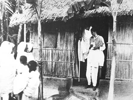 Gandhiji coming out from a hut in Noakhali.jpg